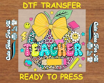 May include: A colorful DTF transfer design with the word "TEACHER" in bubble letters. The design includes an apple with a bow, pencils, a book, and other school-themed graphics. The text "DTF TRANSFER" and "READY TO PRESS" are also included.
