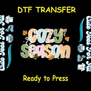 May include: A black background with the words "DTF TRANSFER" in yellow. The words "COZY SEASON" are in a patchwork design with fall leaves and bows. The text "Ready to Press" is in yellow. The phrase "Cute Tees For All" is on the left and right sides.