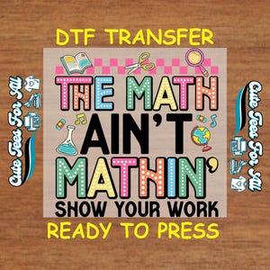 May include: A DTF transfer design with the text "THE MATH AIN'T MATHIN'" in colorful letters, along with the phrases "SHOW YOUR WORK" and "READY TO PRESS." The design includes illustrations of school supplies like a book, scissors, and a magnifying glass.