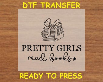 May include: A black and white design of a stack of books with a bow on top. The text "PRETTY GIRLS read books" is below the image. The text "DTF TRANSFER READY TO PRESS" is above and below the image.