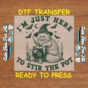 May include: A DTF transfer design featuring a cat wearing a witch hat, stirring a cauldron. The text reads "I'M JUST HERE TO STIR THE POT READY TO PRESS". The design includes bats, candles, and stars, with the words "Cute Tees For All" on the side.
