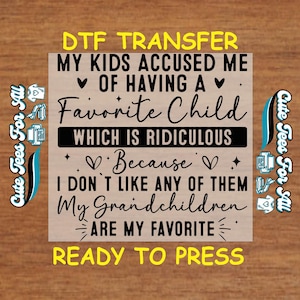 May include: A brown wooden sign with a white background and yellow text that reads "DTF TRANSFER MY KIDS ACCUSED ME ♥ OF HAVING A ♥ FAVORITE CHILD WHICH IS RIDICULOUS ♥ Because ♥ I DON'T LIKE ANY OF THEM My Grandchildren ARE MY FAVORITE ♥ READY TO PRESS".