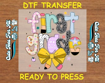 May include: A colorful DTF transfer design for first grade, featuring the words "First Grade" in a playful font with a pencil and bow illustration. The design includes the text "Ready to Press" and "Cute Tees For All".