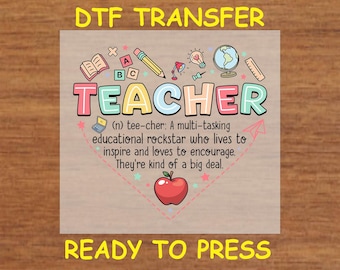 May include: A ready-to-press iron-on transfer design featuring a colorful illustration of the word "TEACHER" with school supplies and a red apple. The text below defines "teacher" as a multi-tasking educational rockstar who lives to inspire and encourage.