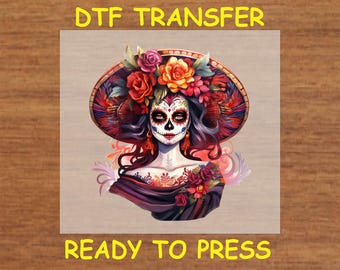 May include: A DTF transfer design featuring a woman with a sugar skull makeup design, wearing a red, black, and white hat with flowers. The design is ready to press.