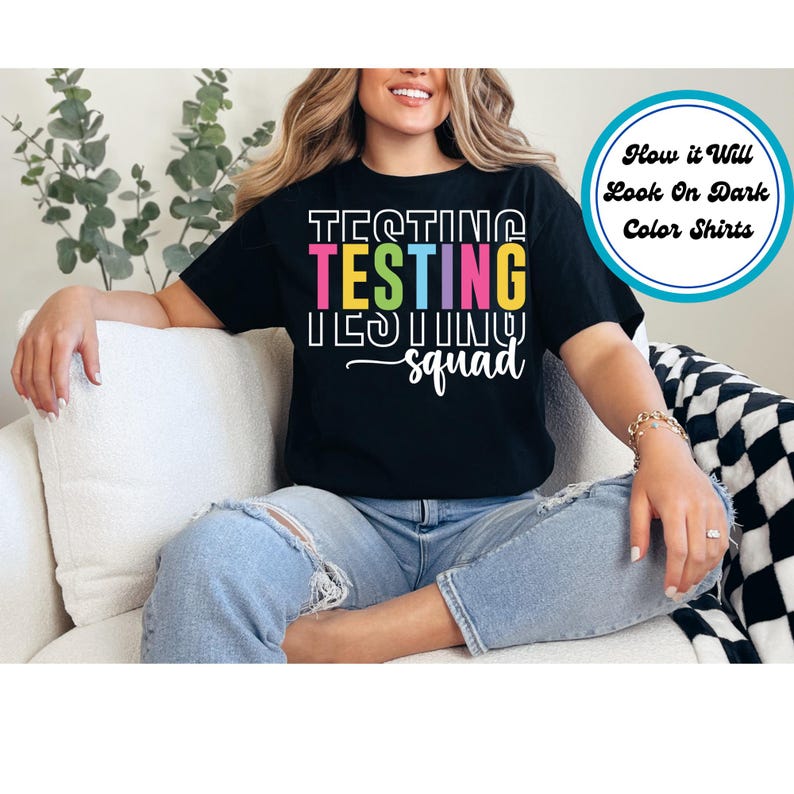 May include: Black t-shirt with the text "Testing Testing Testing Squad" in rainbow colors. The text is stacked vertically with each word in a different color.