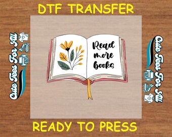 May include: A DTF transfer sheet with a design of an open book with a yellow flower and the text "Read more books". The sheet is ready to be pressed onto a t-shirt or other fabric.