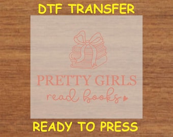 May include: A pink and white DTF transfer sheet with a stack of books tied with a ribbon and the text "PRETTY GIRLS read books" with a pink heart. The text "DTF TRANSFER" and "READY TO PRESS" are in yellow.