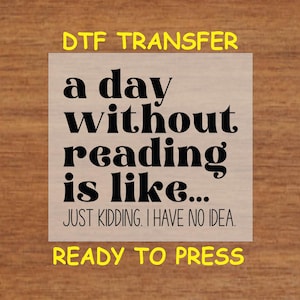 May include: A white iron-on transfer sheet with black text that reads "a day without reading is like... JUST KIDDING. I HAVE NO IDEA." and "DTF TRANSFER" and "READY TO PRESS" in yellow text.