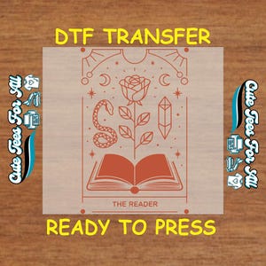 May include: A DTF transfer design featuring a rose, snake, crystal, and open book with the text "THE READER". The design is ready to be pressed onto a t-shirt.