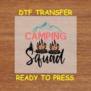 May include: A DTF transfer design featuring the words "CAMPING Squad" in a script font, with a mountain range and campfire graphics. The design includes the text "READY TO PRESS" in yellow.