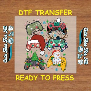 May include: DTF transfer design featuring six game controllers with holiday themes. Controllers are decorated with Santa hats, Christmas lights, and a snowman. The text "DTF TRANSFER" and "READY TO PRESS" are displayed in yellow.