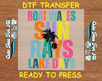 May include: A ready-to-press DTF transfer design featuring the text "Boat Waves Sun Rays Lake Days" in a colorful, layered font with palm trees.