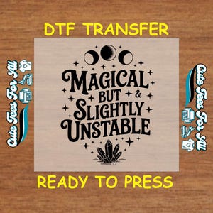 May include: A DTF transfer with the text "MAGICAL BUT SLIGHTLY UNSTABLE" in black, featuring moon phases, stars, and a crystal design. The words "DTF TRANSFER" and "READY TO PRESS" are in yellow.