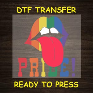 May include: Rainbow-colored lips with a tongue sticking out, and the word "PRIDE!" in rainbow colors. The text "DTG TRANSFER READY TO PRESS" is below the image.