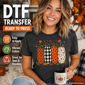 May include: A dark gray short-sleeve t-shirt featuring a graphic of four pumpkins with different patterns including leopard print, black and white buffalo check, orange polka dots, and a floral design, accented with small autumn leaves.