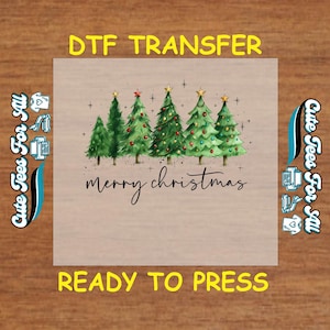 May include: A DTF transfer featuring a watercolor design of six Christmas trees in varying shades of green. The trees are decorated with ornaments and topped with stars. The words "merry christmas" are written in cursive below the trees. The text "DTF TRANSFER" and "READY TO PRESS" are also present.