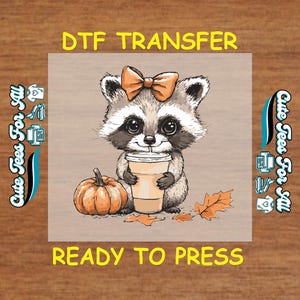 May include: DTF transfer featuring a raccoon with a bow, holding a coffee cup, and a pumpkin. The text "DTF TRANSFER" and "READY TO PRESS" are displayed. The design includes fall leaves and the text "Cute Tees For All".