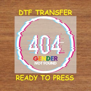 May include: A white circle with a glitched 404 error message and the text "GENDER NOT FOUND" in rainbow colors. The text "DTG TRANSFER READY TO PRESS" is below the circle.