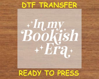 May include: White iron-on transfer sheet with the text "In my Bookish Era" in a stylized font with stars on either side of the text. The sheet is ready to be pressed onto fabric.