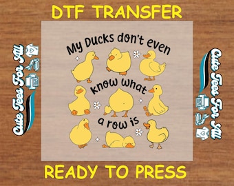 May include: A DTF transfer design featuring yellow cartoon ducks with the text "My Ducks don't even know what a row is." The design also includes the text "DTF TRANSFER" and "READY TO PRESS."