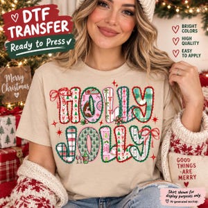 May include: A beige t-shirt featuring the text HOLLY JOLLY in large, patterned letters. The design includes red, green, and pink holiday motifs like trees, bows, and wine bottles. Text on the image reads DTF TRANSFER, BRIGHT COLORS, HIGH QUALITY, EASY TO APPLY, MERRY CHRISTMAS, and GOOD THINGS ARE MERRY.
