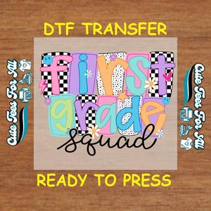 May include: A colorful DTF transfer design for "First Grade Squad". The design features the words "First Grade Squad" in a playful, multi-colored font with decorative elements like flowers, lightning bolts, and smiley faces. The text "Ready to Press" is also included.