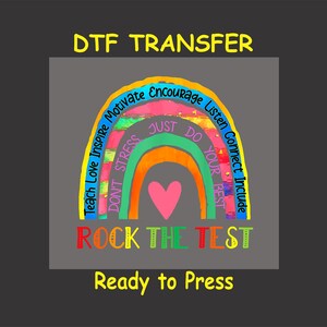 May include: A rainbow-colored design with the words "Teach Love Inspire", "Don't Stress", "Just Do Your Best", "Motivate Encourage Listen Connect Include" and "Rock the Test". The design is on a gray background with the words "DTF Transfer" and "Ready to Press" in yellow.