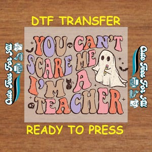 May include: A DTF transfer with the text "You Can't Scare Me I'm a Teacher" in retro bubble letters. A ghost holding a pencil is in the center. The words "DTF Transfer" and "Ready to Press" are at the top and bottom.