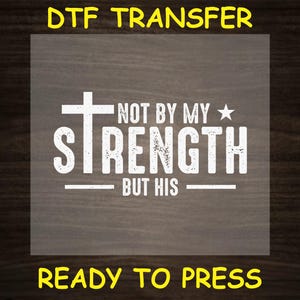 May include: White iron-on transfer design with a cross and the text "Not by my strength but his" on a wood background. The design is ready to press.