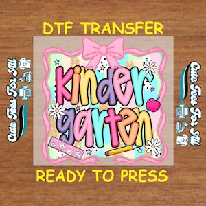 May include: A colorful DTF transfer design with the words "Kindergarten" in bubble letters. The design includes a pink bow, daisies, stars, a ruler, a pencil, and an apple. The text "Ready to Press" is at the bottom.