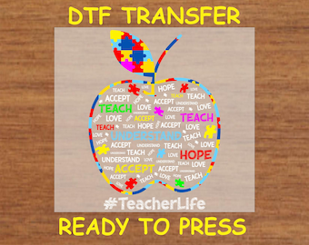 May include: A white apple-shaped design with the words "Teach, Love, Accept, Hope, Understand" repeated around the outline. The apple has a green stem and a puzzle piece design in the center. The text "#TeacherLife" and "Ready to Press" are below the apple.