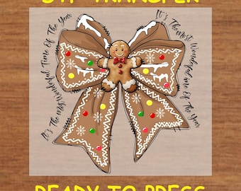 May include: A brown gingerbread bow with white icing and red and green sprinkles. A gingerbread man is in the centre of the bow. The text "It's The Most Wonderful Time Of The Year" is written around the bow.