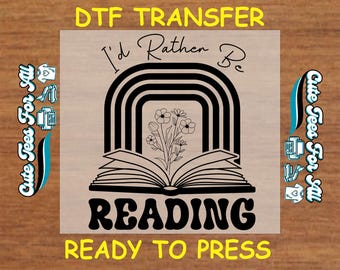 May include: A black and white design of a rainbow with a book and flowers in the center. The text "I'd Rather Be Reading" is above the book and "READY TO PRESS" is below the book.