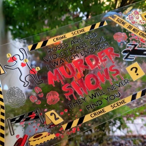 May include: Clear acrylic bookmark with crime scene theme. Features text "Roses are red, violets are blue, I watch enough murder shows, they will never find you." Includes crime scene tape, footprints, and a body outline.