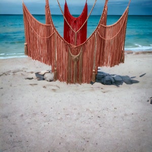 Pode incluir: Três tapeçarias de macramé de parede com franjas, duas são bege e uma é vermelha.