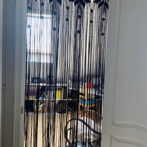 Peut inclure: Rideau en macram&eacute; noir avec un motif g&eacute;om&eacute;trique suspendu dans une porte. Le rideau est fait d'un cordon &eacute;pais et a une frange en bas.