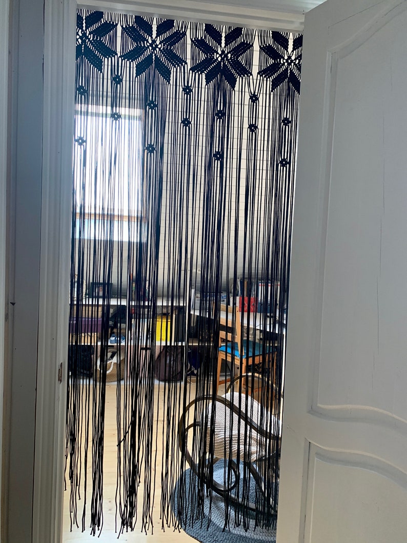 Peut inclure: Rideau en macram&eacute; noir avec un motif g&eacute;om&eacute;trique suspendu dans une porte. Le rideau est fait d'un cordon &eacute;pais et a une frange en bas.