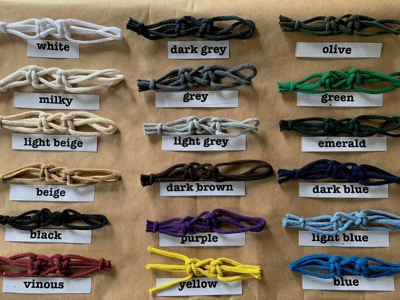 May include: A collection of 18 different colored cords tied in a knot. The cords are labeled with their color names: white, dark grey, olive, milky, grey, green, light beige, light grey, emerald, beige, dark brown, dark blue, black, purple, light blue, vinous, yellow, and blue.