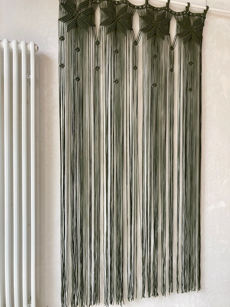Peut inclure: Une suspension murale en macram&eacute; verte avec un motif d'&eacute;toile. La suspension est faite de plusieurs fils de laine et mesure environ 90 cm de haut.