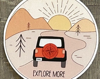 May include: A round sticker with a cartoon illustration of a jeep driving on a winding road towards a sunset. The jeep is red and black with a compass on the back tire. The text "EXPLORE MORE" is printed below the jeep.