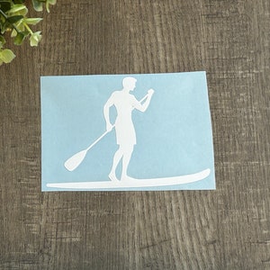 May include: White silhouette of a person paddleboarding on a blue background.