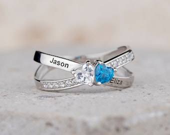 May include: A silver ring with two small heart-shaped stones. The ring is engraved with the names "Jason" and "Eliza".