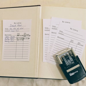 May include: A book with a blank page and a bookplate with the text "Ex Libris David Alan" and the title "The Art of War" by "Sun Tzu". The bookplate has a list of borrowers and dates. There are four blank bookplates with the text "Ex Libris" and a black rubber stamp with the text "ExcelMark Pro".