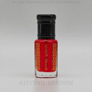 May include: A small, red perfume bottle with a black cap. The bottle features gold and red decorative patterns and the text "ATTYYAH LONDON" in gold. The bottle is on a white background.