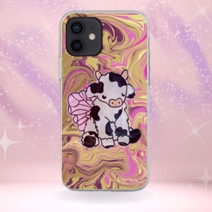 May include: A clear phone case featuring a cartoon cow with pink fairy wings. The cow has black and white spots. The background has a swirling pattern of gold, pink, and purple. The phone case is on a pink background.