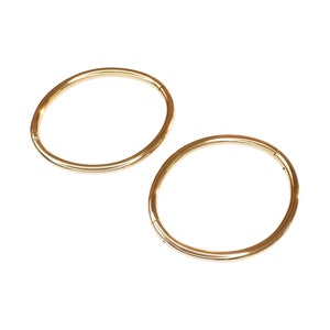May include: Two gold hoop earrings, each with a smooth, circular design.