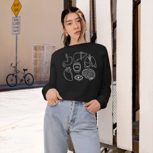 May include: Black cropped sweatshirt with a white outline of various human organs, including a heart, brain, lungs, stomach, eye, and mouth.