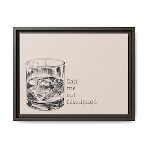 May include: A framed print featuring a sketch of a cocktail glass filled with ice and a lemon slice. The text "Call me old fashioned" is printed in a simple font on a beige background.