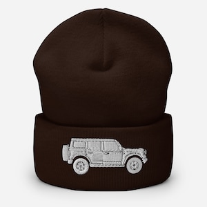 May include: A brown knitted beanie with a white embroidered image of a Land Rover Defender.